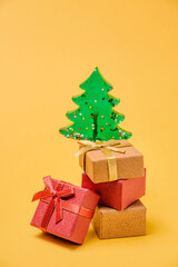 Gift boxes and a Christmas tree on a yellow background with copy space.