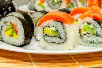 Delicious fresh sushi close-up on a white plate and a black table. Japanese cuisine.