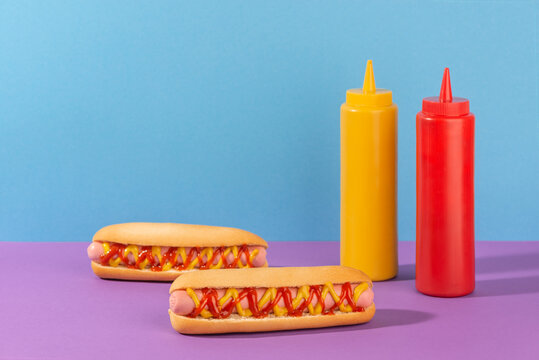Two juicy hotdogs and squeeze bottles of mustard and ketchup