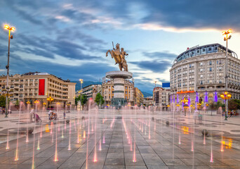 Skopje, North Macedonia - 01.08.2020: Square Macedonia in Skopje at sunset with dancing illuminated fountains and statue of Alexander the Great (warrior on horse) at background - obrazy, fototapety, plakaty