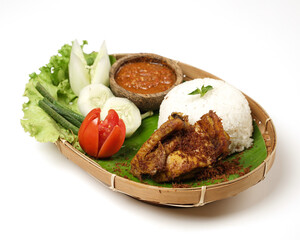 Fried chicken with ripe golden skin laid out on a wooden sheet on a white background, plus white rice, chili sauce and various vegetables, view from above. commonly used for menus and picture packs.