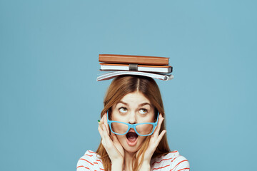 Female student with books on her head science education blue background emotions gesturing with...
