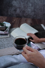 Woman's hand reading a coffee cup in a darkened bedroom