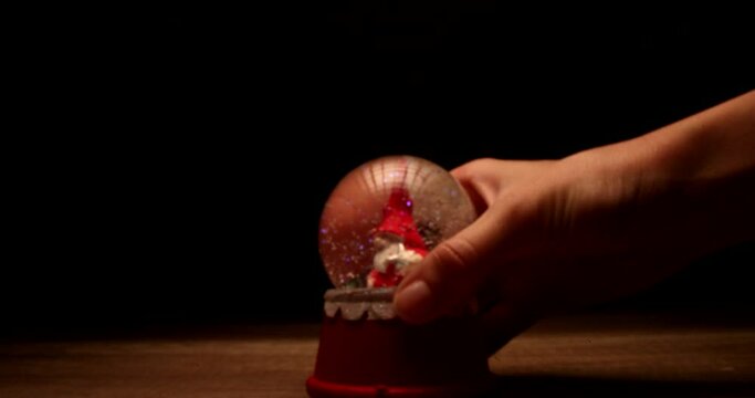 Slow motion footage of snow falling on Santa Claus in magical glass ball. Christmas concept