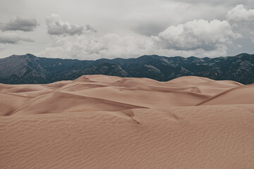 Fototapeta na wymiar A view of giant desert sand dunes and the surrounding Sangre De Cristo Mountains in Great Sand Dunes National Park in Colorado, USA.