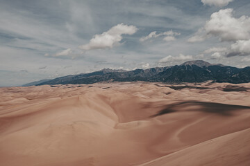 A view of giant desert sand dunes and the surrounding Sangre De Cristo Mountains in Great Sand Dunes National Park in Colorado, USA.