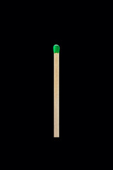 A single wooden match with a green head, isolated on a black background.