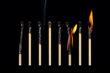 A set of different burnt matches, with smoke, with different fire, isolated on a black background.