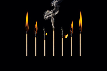 Fototapeta premium An extinct match in a group of burning matches, the concept of emotional burnout, work-life balance