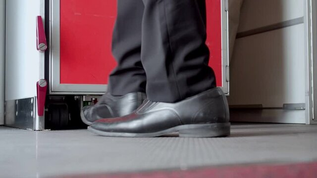 male cabin crew release break of service trolley cart from aircraft galley storage. flight attendant unlock cart and pull.