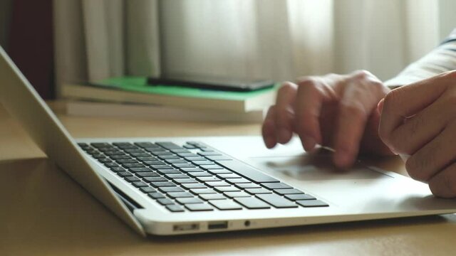 Selective focus at Asian men hand while type on computer keyboard and study online learning class at home. Social distance concept new normal lifestyle that people can work or do home school.
