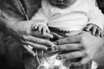 Close up of beautiful little hand of cute baby girl, in caring father arms, tender family moments, toddler first winter holidays, Christmas and New Year celebration concept