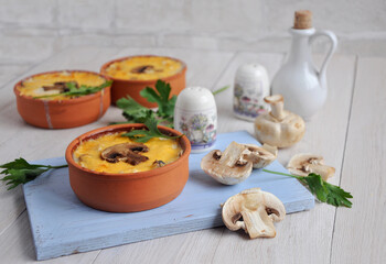 Homemade mushroom julienne in ceramic cocotte. Sliced champignons. Porcelain salt shaker.