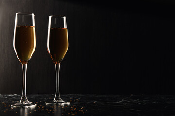 Two glasses of champagne, wine on a black background, a place for text on the right, copypace. New year and Christmas background