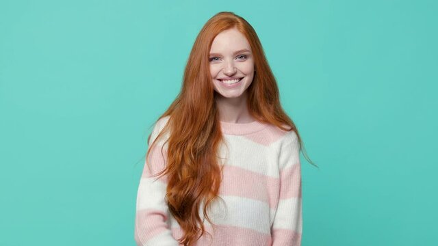 Secret pretty ginger redhead young girl in white pink sweater isolated on blue turquoise background studio. People lifestyle concept. Looking camera say hush be quiet with finger on lips shhh gesture