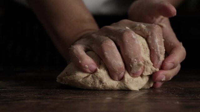 Slow Motion shot of  bakery chef kneeding dough on wooden table. Baking concept.