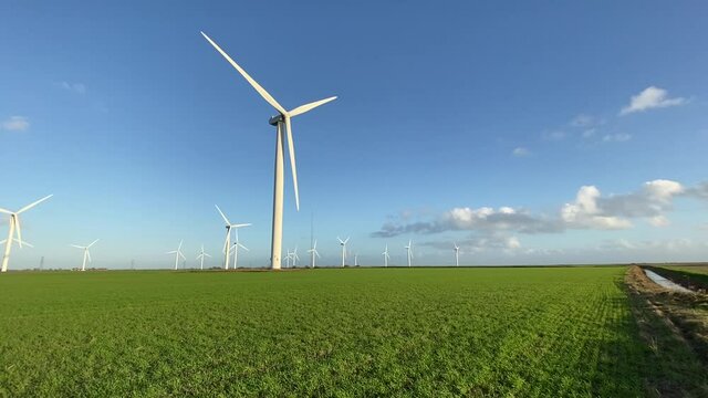 Wind farm turbines that produce electricity energy. Windmill Wind power technology sustainable Wind turbines standing in green field - stock footage