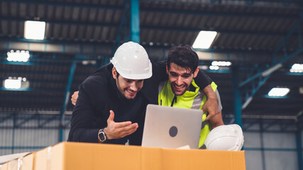 Two factory worker celebrate success together in the factory or warehouse . Industry work achievement concept .