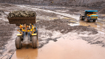     Dump truck and wheel loader in operation. Mining.   A wheel loader loads mountain soil into the body of a dump truck.  © Letopisec