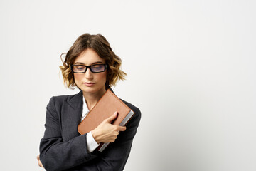 Woman at work with book in hand light background classic suit glasses head