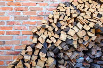 Brick wall with Wooden logs,boards, firewood. Harvesting firewood for the winter. Lumber for furniture making. Texture of wooden materials