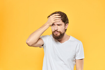 Fototapeta na wymiar Bearded man in a white T-shirt gestures with his hands emotions studio yellow background