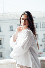 Fototapeta premium Portrait of a beautiful fashionable brunette woman in a white men's shirt