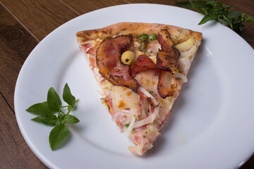 Pizza slice served on the plate. Portuguese pizza made with ham, pea egg, heart of palm, pepperoni, onion and mozzarella and bacon. Basil leaves to decorate. restaurants and Pizzerias.