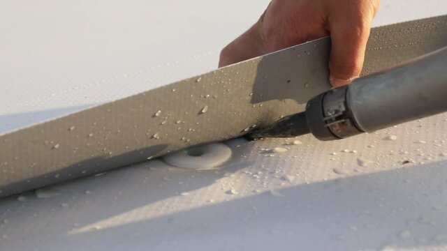 Roofer use hot air gun to weld synthetic PVC membrane.