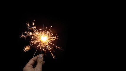 Silvester Party / New Year celebration festive background banner - Young happy pretty woman holding a sparkling sparkler in her hand at dark night