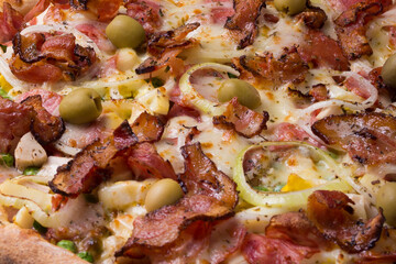 Tasty Portuguese Pizza made with ham, pea egg, heart of palm, pepperoni, onion and mozzarella and bacon. Close-up photograph of the pizza filling. Restaurant. and Pizzeria.