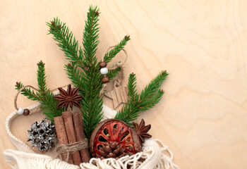Spruce branch in an eco-friendly paper bag and Christmas decorations on wooden background. Assortment of cozy hygge Xmas. DIY, zero waste, eco friendly.  Flat lay, top view.