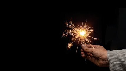 Silvester Party / New Year celebration festive background banner - Young happy pretty woman holding a sparkling sparkler in her hand at dark night