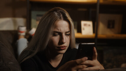Young unhappy blonde woman lying on sofa received a bad message or had a bad incident on the phone