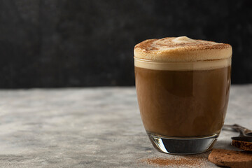 Glass of coffee drink with whipped milk, dark background.
