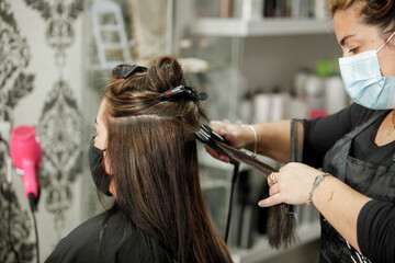 Fototapeta premium Woman with face mask getting a fresh style at a hair salon. Woman getting a hair wash. Hairdressing concept.