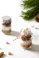 Obraz na płótnie Canvas Tasty edible Christmas gift in glass jar for making chocolate beverage on light background. Xmas treats.