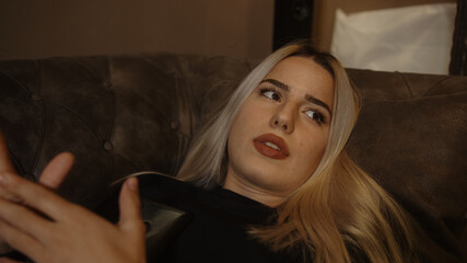 Young unhappy blonde woman lying on sofa received a bad message or had a bad incident on the phone