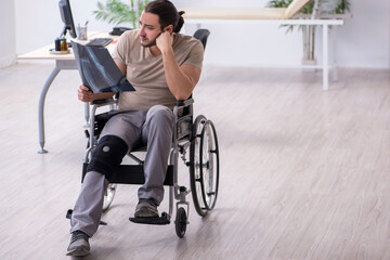 Fototapeta na wymiar Young leg injured man in wheel-chair looking x-ray