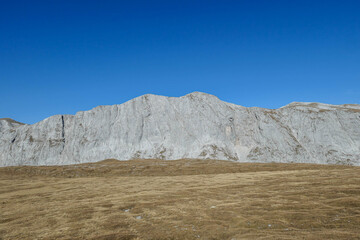 A panoramic view on the plain on top of a mountain in Hochschwab region in Austrian Alps. The flora overgrowing the slopes is turning golden. Autumn vibes. Many mountain chains in the back. Wilderness