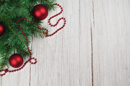 firry branches with red balls and a red garland on a light wood background. Christmas decorations. Christmas tree. New year.
