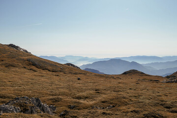A panoramic view on the plain on top of a mountain in Hochschwab region in Austrian Alps. The flora overgrowing the slopes is turning golden. Autumn vibes. Many mountain chains in the back. Wilderness