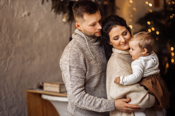 Caring parents with little baby girl spend winter holidays at home, loving mother hold cute toddler in arms, enjoy family moments, Christmas and new year celebration concept