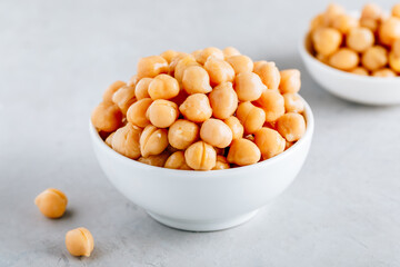 Cooked Chickpeas in white bowl on gray stone background