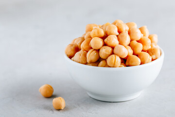 Cooked Chickpeas in white bowl on gray stone background