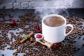 White cup full of coffee beans , red flowers and red chocolate candy against the background of a dark brick wall. Morning espresso. Coffee mug.	