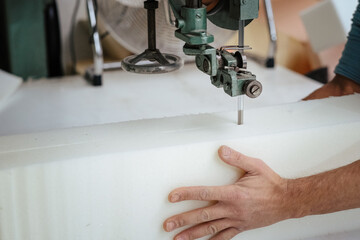 Furniture maker cutting an upholstery foam using a foam cutter machine - obrazy, fototapety, plakaty