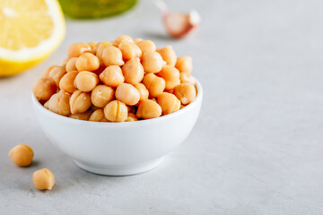 Cooked Chickpeas in white bowl on gray stone background