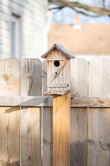 birdhouse has been mounted to a wooden fence