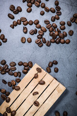 Coffee beans on a wooden pallet and dark grey background. Coffee break. Morning espresso.	